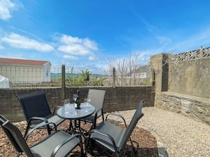 An outdoor patio with a round table and four chairs, a bottle of wine, and a glass. - Mulberry House - close to BPW and Brecons (Dowlais)