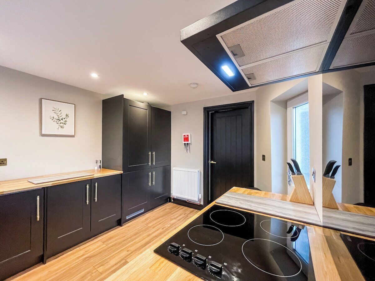 A modern kitchen with black cabinets, a wooden countertop, and a black induction cooktop.