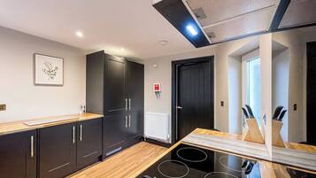 A modern kitchen with black cabinets, a wooden countertop, and a black induction cooktop.
