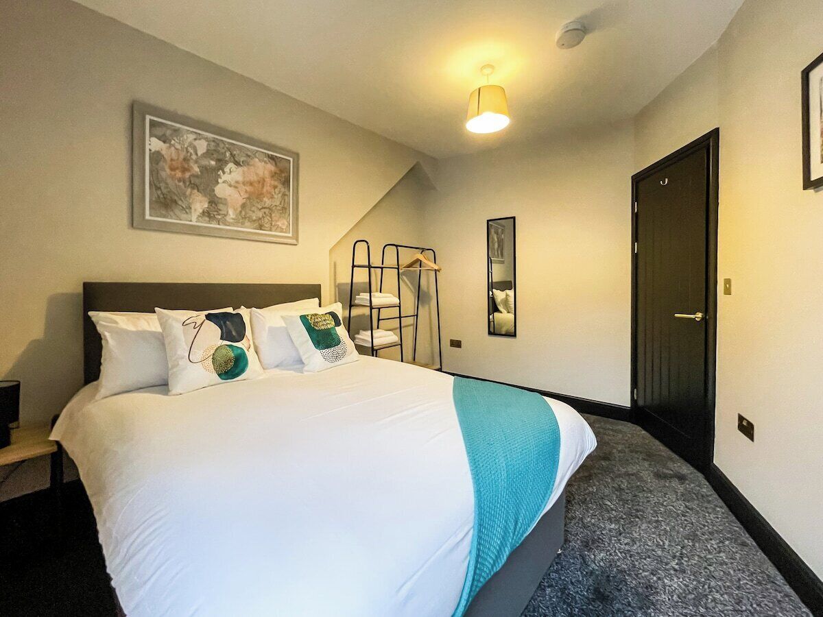 A hotel room with a bed, a painting on the wall, a staircase, and a door.