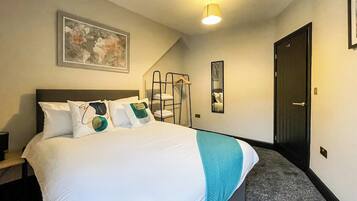 A hotel room with a bed, a painting on the wall, a staircase, and a door.