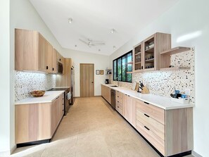 A modern kitchen with wooden cabinets, a microwave, and a refrigerator. - Charming 3-bedroom house with AC in Playa Negra Playa Viejo (Playa Negra, Puerto Viejo de Talamanca)