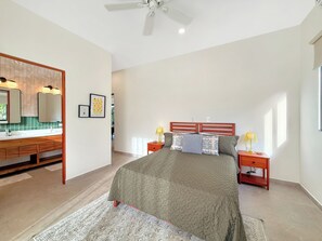 A bedroom with a bed, bedside tables, a vanity with a mirror, and artwork on the walls. - Charming 3-bedroom house with AC in Playa Negra Playa Viejo (Playa Negra, Puerto Viejo de Talamanca)