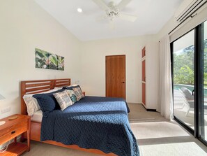 A bedroom with a bed, bedside table, and a view of a swimming pool through a glass door. - Charming 3-bedroom house with AC in Playa Negra Playa Viejo (Playa Negra, Puerto Viejo de Talamanca)