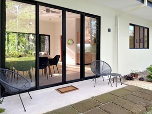 Un espace extérieur moderne, aménagé avec des sièges, une porte vitrée donnant accès à un espace intérieur, une petite table et deux chaises.