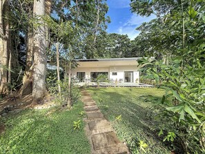 A modern house with a paved pathway leading to a covered outdoor seating area. - Charming 3-bedroom house with AC in Playa Negra Playa Viejo (Playa Negra, Puerto Viejo de Talamanca)