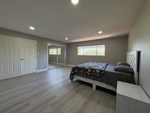 Une chambre à coucher avec un lit, une fenêtre et une porte donnant sur une autre pièce.