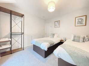 Une chambre avec deux lits, une armoire et un radiateur.