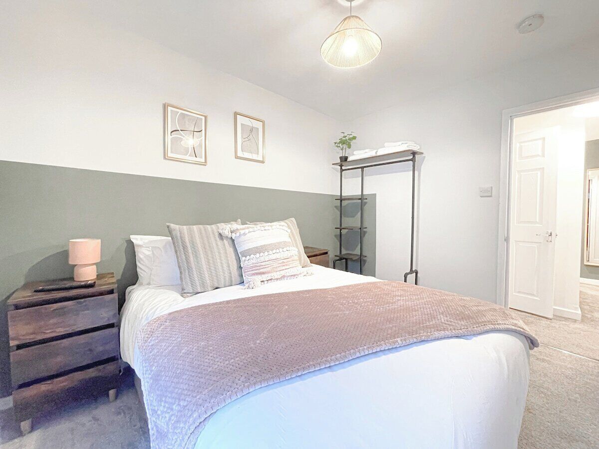 A bedroom with a bed, bedside tables, a mirror, and a door.