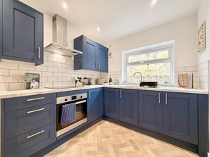A modern kitchen with dark blue cabinets, a white countertop, and a herringbone-patterned floor.
