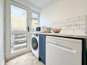 A compact kitchen with a washing machine, dishwasher, and microwave.