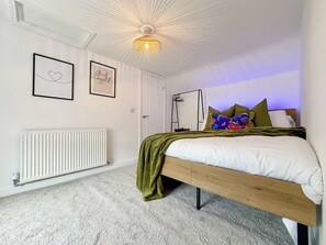 A bedroom with a bed, a radiator, a door, and wall art.