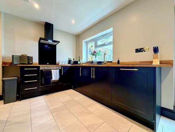 A modern kitchen with dark cabinetry, a microwave, and a window with a view of greenery.