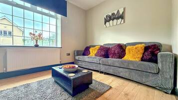 A modern living room with a sofa, a coffee table, and a window with a view.
