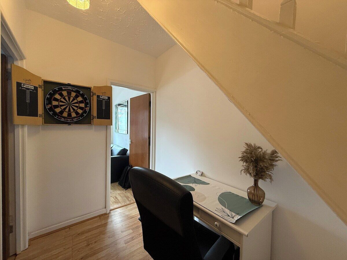 Ein Flur mit Schreibtisch, Stuhl und Dartscheibe an der Wand.