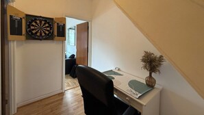 A hallway with a desk, a chair, and a dartboard on the wall.