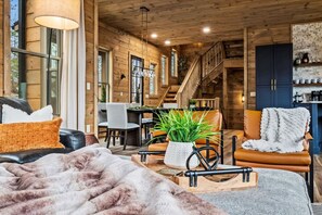 A cozy cabin interior with a dining area, a staircase, and a kitchen. - Mtn Cabin w/ Hot Tub, Fire Pit & EV Charger (Sevierville)