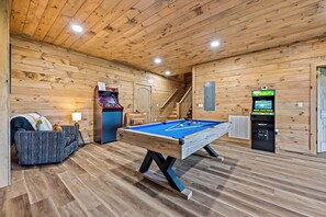 A pool table in a room with wooden walls and a ceiling, a sofa, and a staircase. - Mtn Cabin w/ Hot Tub, Fire Pit & EV Charger (Sevierville)