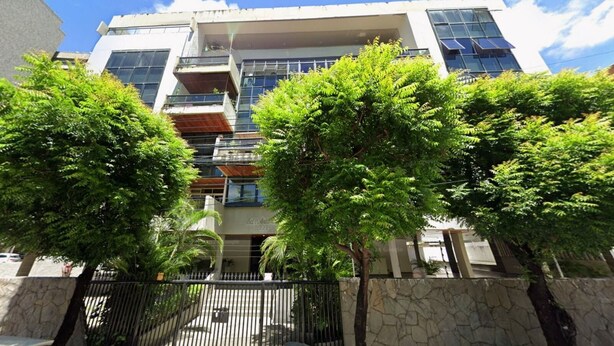 A multi-story building with balconies, a stone wall, and trees in front. - Raridade Ape 4 Quartosmeirelesbeira Mar180m2 (Fortaleza)