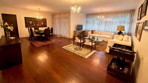 A living room with a dining area, a sofa set, a chandelier, and a painting on the wall. - Raridade Ape 4 Quartosmeirelesbeira Mar180m2 (Fortaleza)
