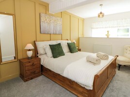 Un dormitorio con cama de madera, una mesita de noche, un espejo y una ventana con cortinas.