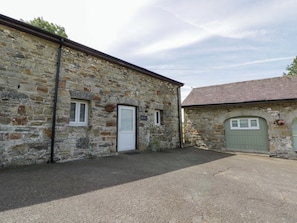 A stone building with a white door, a window, and a green door. - Shearers (Llandysul)