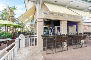 Ein Außenbereich mit Barbereich, Poolkapazitätshinweis, Sitzgelegenheiten und einer TIKI-Bar.
