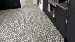 A modern kitchen with white cabinets, a black countertop, a washing machine, and patterned floor tiles. - Coastal Getaway 5-bed Sleeps 10 | DN35 (North East Lincolnshire)