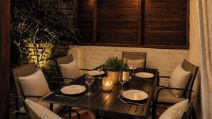 An outdoor patio with a table set for dining, surrounded by chairs, under a covered area with string lights. - Coastal Getaway 5-bed Sleeps 10 | DN35 (North East Lincolnshire)