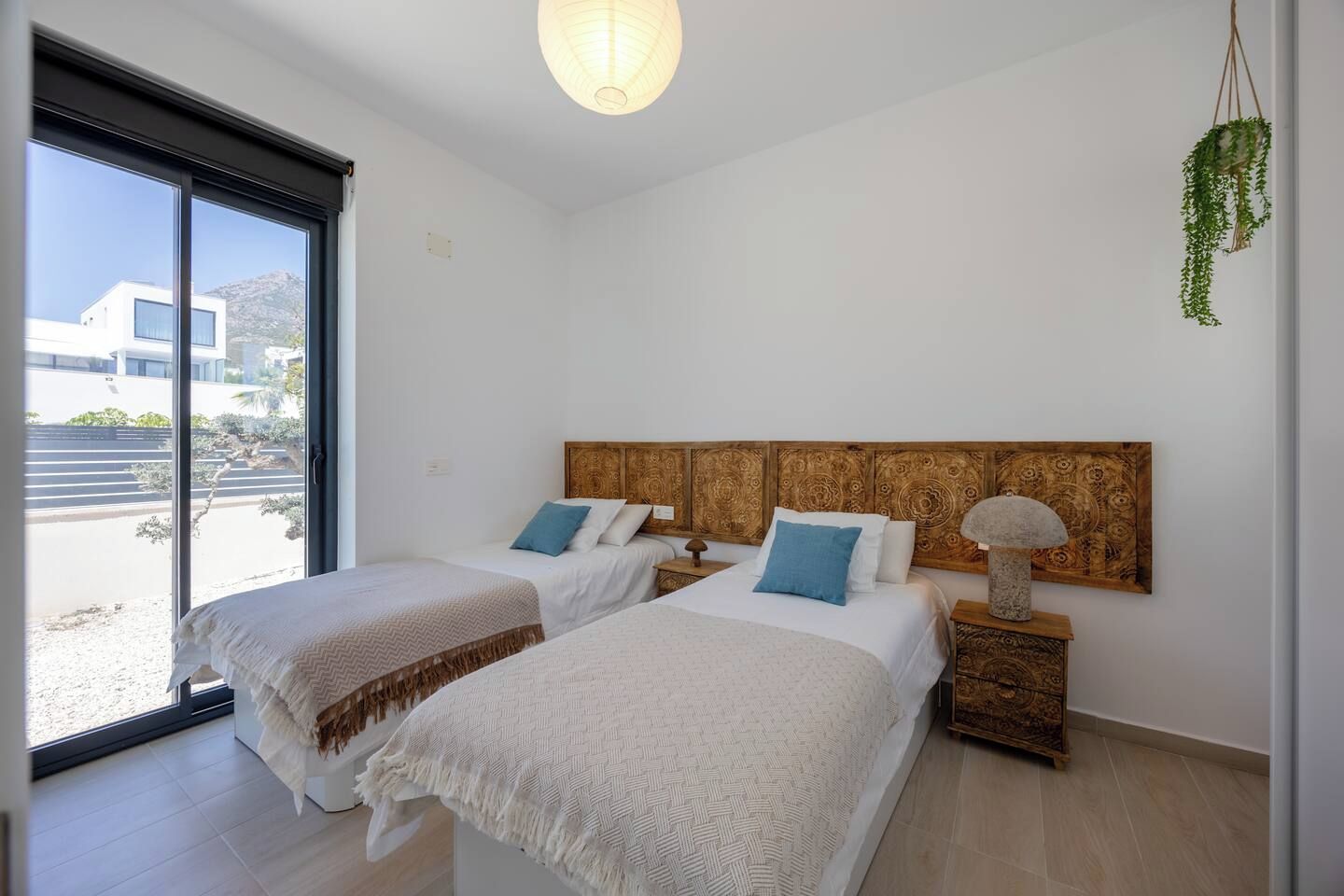 A hotel room with two beds, a large window, and a view of the outside.