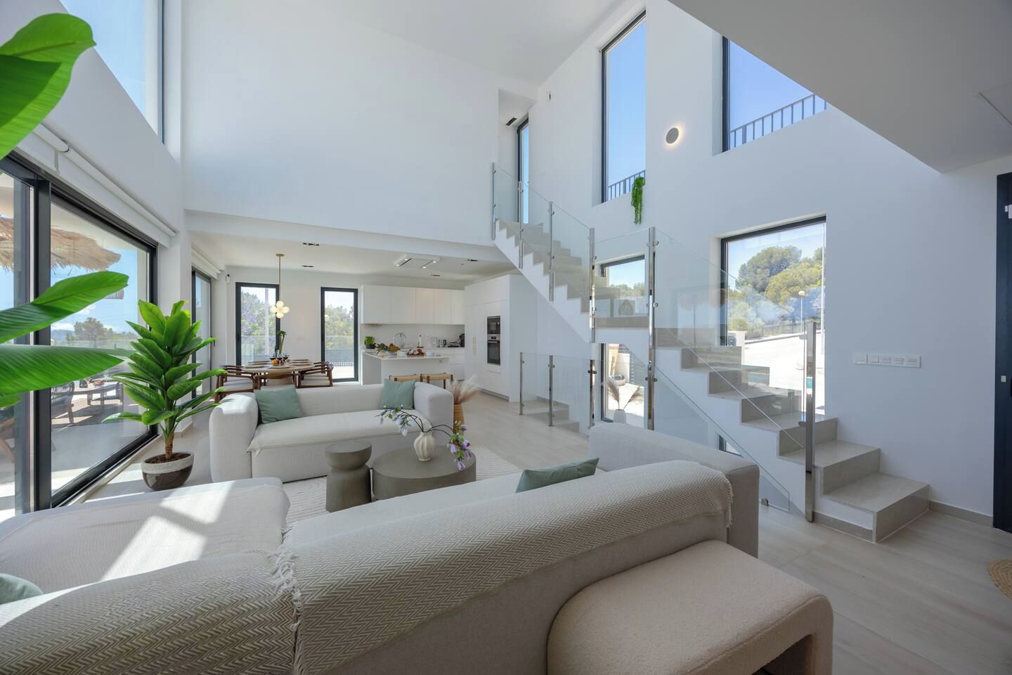 A modern interior with a staircase, a dining area, and a living room with a large window.