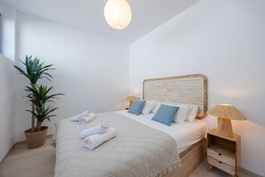 A bedroom with a bed, bedside table, lamp, potted plant, and a hanging light fixture. - Luxury Pool Villa by Fidalsa (Polop)