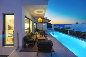 A modern outdoor living area with a pool, seating, and a view of the landscape. - Luxury Pool Villa by Fidalsa (Polop)