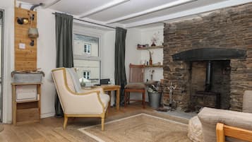 Una sala de estar acogedora con chimenea de piedra, muebles de madera y vistas al exterior.