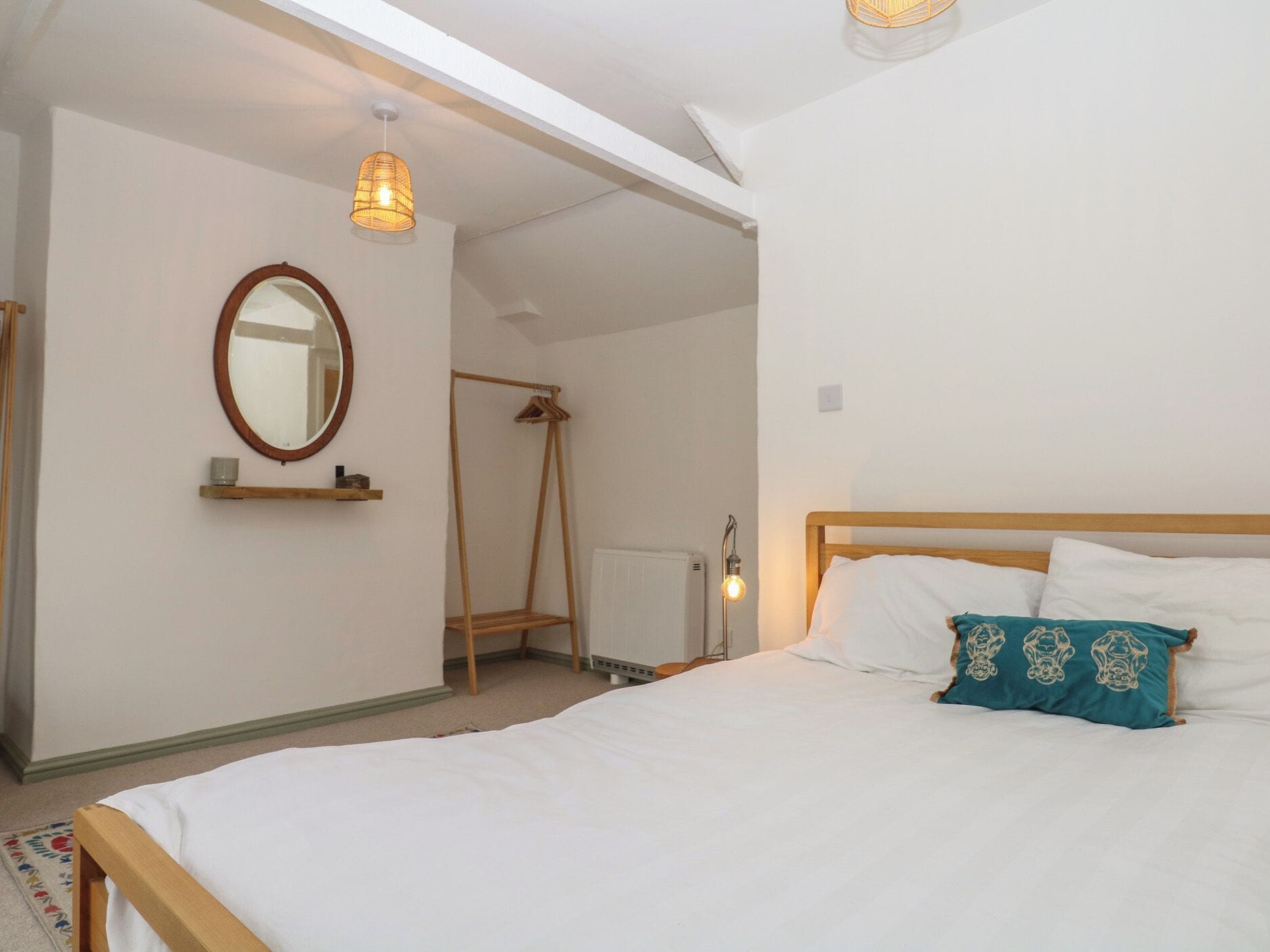 Un dormitorio con una cama, una lámpara colgante, un radiador y un perchero de madera.