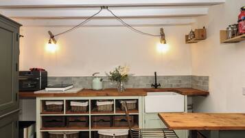 Una cocina con encimera de madera, refrigerador blanco y lámpara colgante.