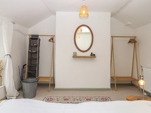 A bedroom with a bed, a hanging chair, a shelf with items, a mirror, a light fixture, and a radiator.