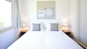 A bedroom with a large bed, two bedside tables with lamps, a window with curtains, and a wall-mounted artwork. - Holiday Home in Belfeld With Terrace (Belfeld)