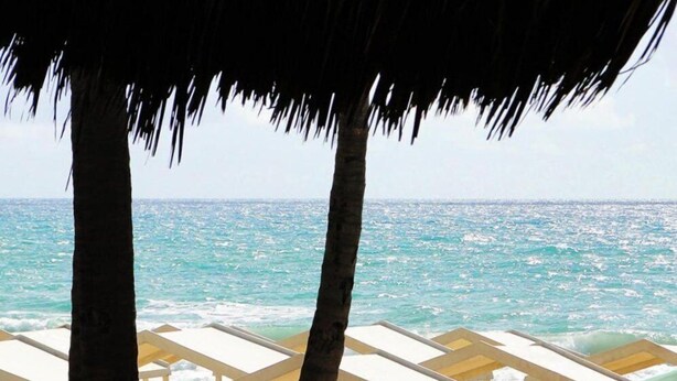 A beach view with a thatched roof, yellow chairs, and a clear ocean. - It's on the sea Balance - Unique Experience in Beautiful Designed Flat, Oceanview 2Q, 2WC (Fortaleza)