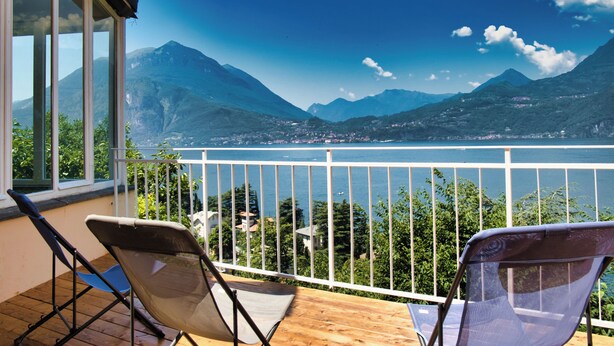 Un balcon avec deux chaises donnant sur un lac et des montagnes.