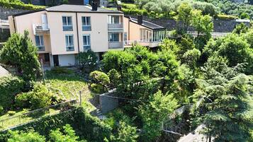 Un edificio a più piani con balconi, immerso nel verde e circondato da mura in pietra.