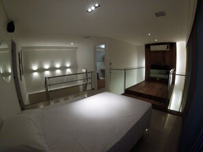 Ein Schlafzimmer mit einem großen Bett, einer Glasreling, einem Badezimmer mit Dusche und einem kleinen Balkon.