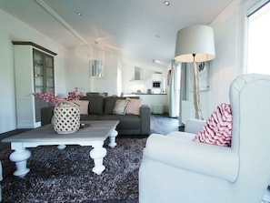 Ein modernes Wohnzimmer mit Sofa, Sessel, Couchtisch und einer Lampe.
