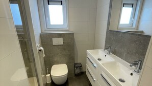 A modern bathroom with a toilet, a sink, a mirror, and a window. - Holiday Home in Susteren With Terrace (Susteren)