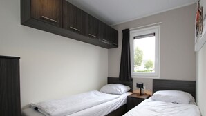A room with two single beds, a window with a view, and a dark wooden wardrobe. - Holiday Home in Susteren With Terrace (Susteren)