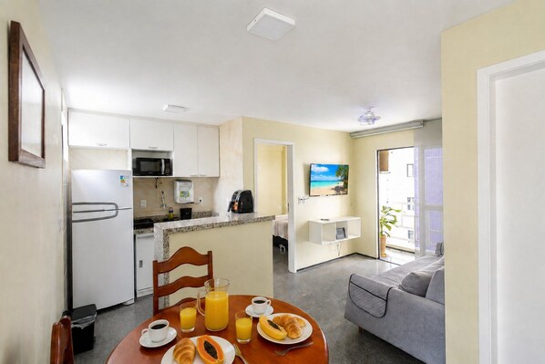 A compact living space with a kitchenette, dining area, and a sofa. - Flat 2 Quartos no Melhor Local de Fortaleza (Fortaleza)