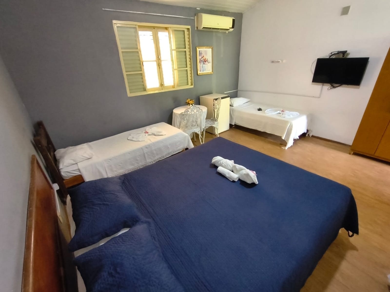 A hotel room with two beds, a desk, a chair, and a television.