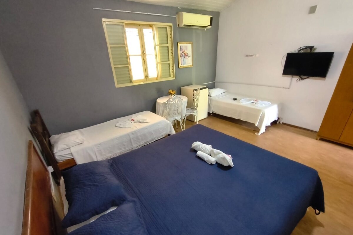 A hotel room with two beds, a desk, a chair, and a television.
