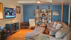 A living room with a television, a bookshelf, a sofa, a chair, and a coffee table. - Lake Anna Waterfront Family & Pet Friendly Retreat! With 5+ BRs 4 BAs. (Spotsylvania Courthouse)
