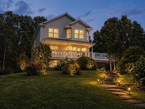 A two-story house with a balcony, surrounded by well-maintained lawns and trees.